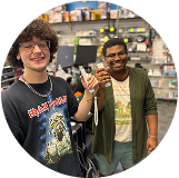 Two people smiling and holding controllers in a game store