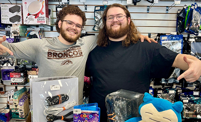 People showing gaming accessories and merchandise on a store counter