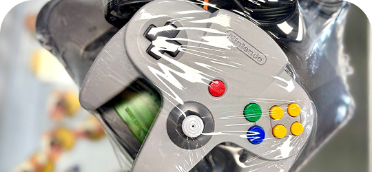 Close-up of a gray Nintendo 64 controller wrapped in protective plastic